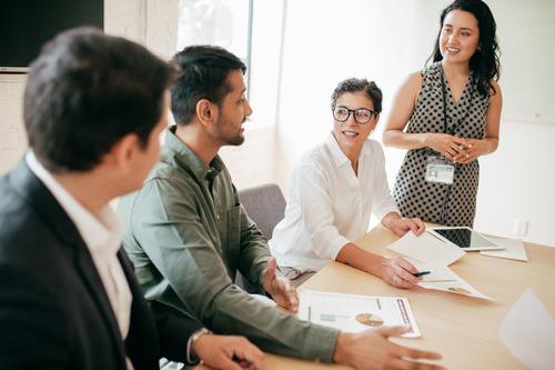 graduate students having a discussion around a table in a modern office setting